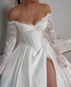 a woman in a white wedding gown with long sleeves and thigh high slits is posing for the camera