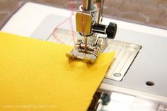 the sewing machine is working on the yellow fabric