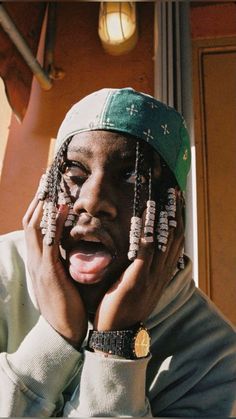 a man with his hands on his face and wearing beads around his head, making a silly face