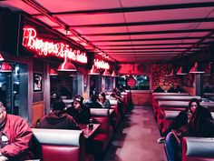 diners sit in booths with red lights on the ceiling and signs lit up above them