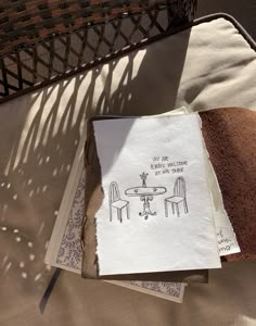 an open book sitting on top of a table next to a basket filled with bread