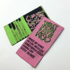 two pink and green patches with black writing on them, one has an image of graffiti