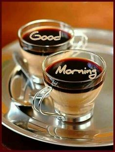 two cups of coffee with the words good morning written on them sitting on a silver tray