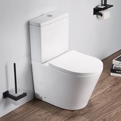 a white toilet sitting on top of a wooden floor next to a wall mounted phone