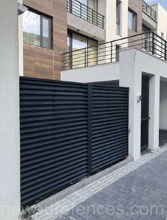 an apartment building with black shutters on the front and side walls, next to a brick walkway