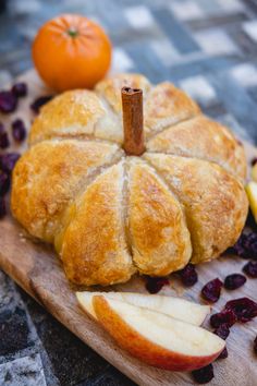 an apple and cranberry bread is on a cutting board with some fruit around it