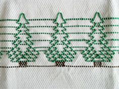 three green trees are on a white towel with stitching in the shape of christmas trees