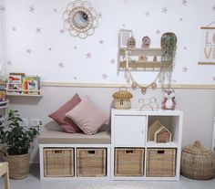 a room with baskets and toys on the floor in front of a wallpapered wall