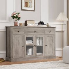 a white couch sitting next to a wooden cabinet with glass doors on top of it