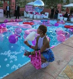 a woman sitting in front of a pool filled with balloons