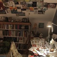 a cluttered living room with bookshelves and pictures on the wall