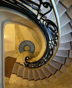 a spiral staircase with wrought iron railing and handrails, looking down at the floor