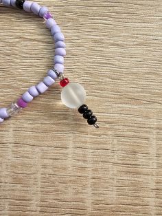 a beaded necklace with two beads and a heart charm on a wooden table top