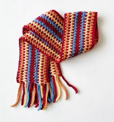 a multicolored knitted scarf laying on top of a white surface