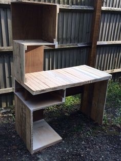 a wooden table sitting in the middle of a yard next to some fenced in wood