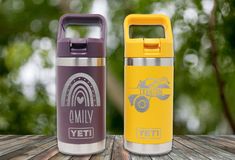 two insulated water bottles sitting on top of a wooden table next to each other