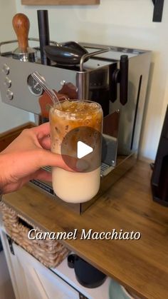 a person is holding a drink in front of an espresso machine