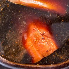 two salmon fillets in a pan with oil and seasoning