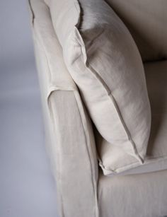 a white couch with two pillows on it's back and the seat upholstered