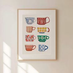 an art print with coffee cups on it in a white frame hanging on the wall