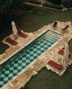 an aerial view of a swimming pool with lounge chairs and umbrellas in the grass