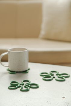 a coffee cup sitting on top of a white table next to some green circles in front of a couch