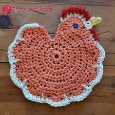 an orange and white crocheted chicken sitting on top of a wooden table