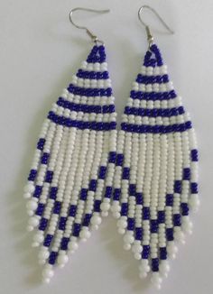 two white and blue beads are hanging from earrings