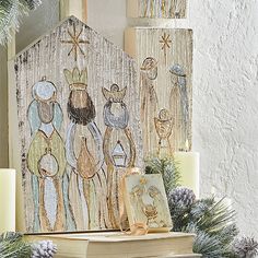 a nativity scene with candles and christmas decorations on a mantle in front of a white wall