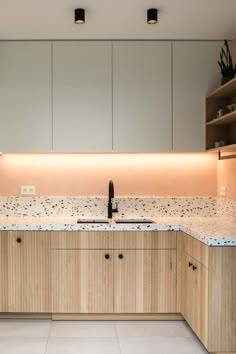 an empty kitchen with wooden cabinets and marble counter tops, along with white tile flooring