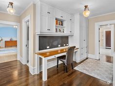 an empty room with white cabinets and wood flooring is seen in this image from the dining area