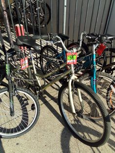 two bikes parked next to each other on the sidewalk in front of a metal fence