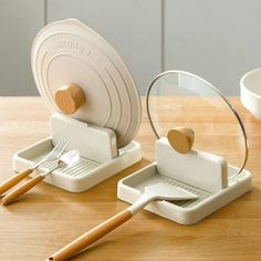 two white dishes with wooden utensils on a table