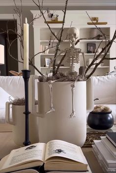 an open book sitting on top of a table next to a candle and skeleton figurine