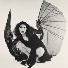 a woman kneeling on the ground holding an open umbrella in front of her face,