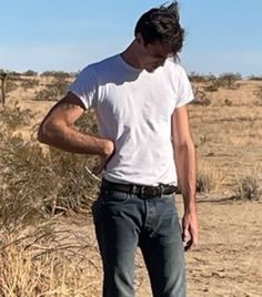 a man standing in the desert with his hands on his hips