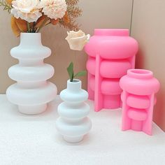 three vases with flowers in them sitting on a table next to each other,