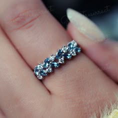 a woman's hand holding a ring with three stones on the middle of it