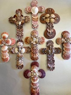 a cross made out of seashells on a white wall next to other shells