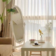 a living room with a table, mirror and couch in front of a window filled with curtains