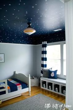 a child's bedroom decorated in blue and white with stars painted on the ceiling