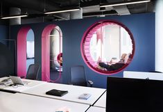 an office with blue walls and pink circular mirrors