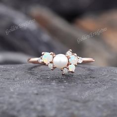 an opal and diamond ring on top of a rock