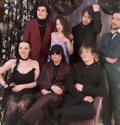 a group of people sitting next to each other in front of a wall covered with curtains