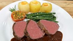 a white plate topped with meat, green beans and potatoes