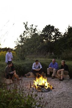 four people sitting around a campfire at dusk