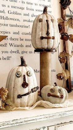 three white pumpkins sitting on top of a mantle next to a wall with writing