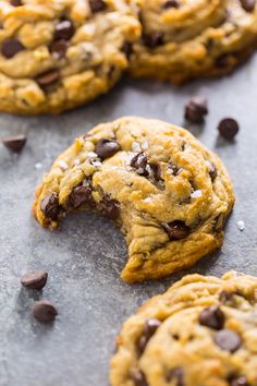 chocolate chip cookies on a baking sheet with one broken in half and the other partially eaten