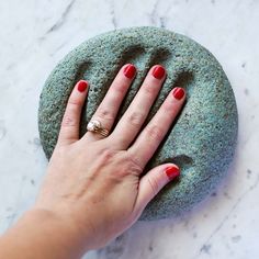 a woman's hand on top of a rock with a ring in the middle