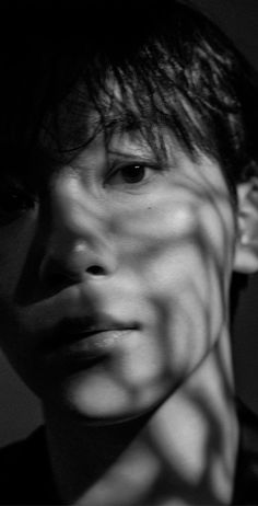 black and white photograph of a man's face with shadow on the wall behind him